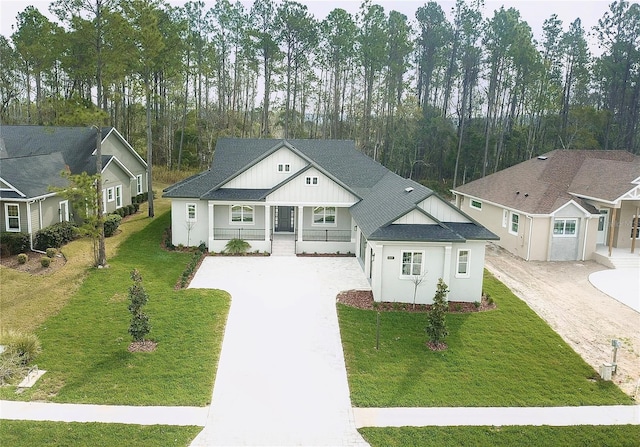 modern inspired farmhouse with covered porch, driveway, a shingled roof, and a front lawn