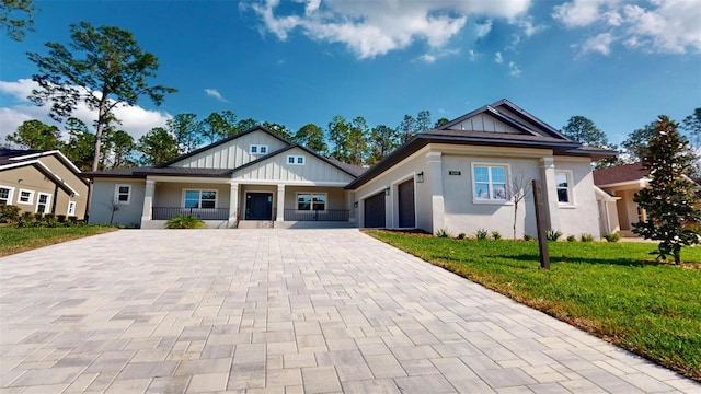 craftsman-style home with stucco siding, a front lawn, decorative driveway, board and batten siding, and a garage