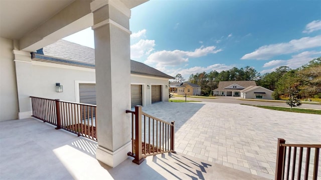 view of patio / terrace featuring an attached garage and driveway