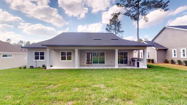 rear view of property with a yard, a patio, and stucco siding