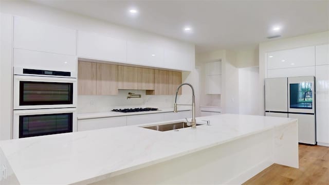 kitchen with white appliances, white cabinets, modern cabinets, and a sink