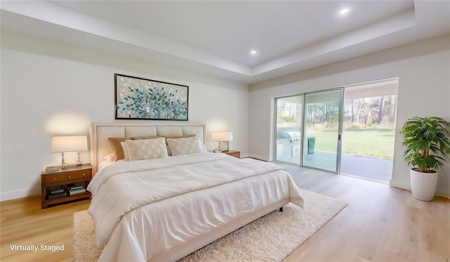 bedroom featuring access to exterior, light wood finished floors, baseboards, a tray ceiling, and recessed lighting