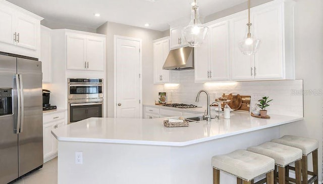 kitchen featuring stainless steel appliances, light countertops, white cabinetry, and under cabinet range hood