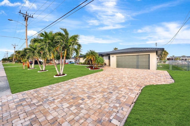 view of front of home featuring decorative driveway, stucco siding, a front yard, fence, and a garage