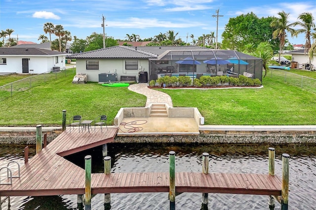 back of house with a lanai, central air condition unit, a water view, fence, and a yard