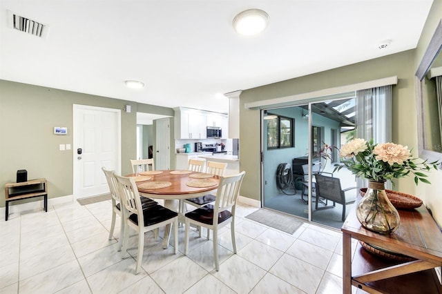 dining space with light tile patterned flooring, visible vents, and baseboards