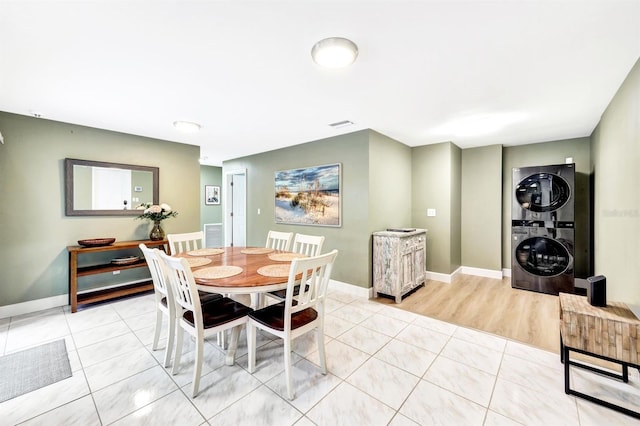 dining area with stacked washer / drying machine, baseboards, and light tile patterned floors