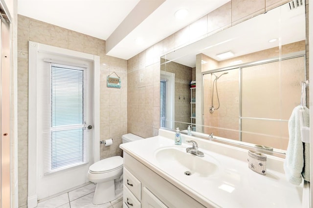 bathroom featuring toilet, a shower with shower door, vanity, tile walls, and tile patterned floors