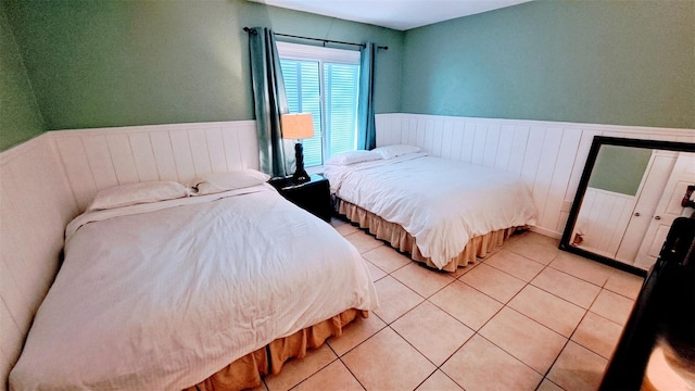 bedroom featuring light tile patterned floors and wainscoting