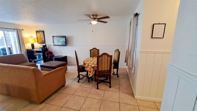 dining space featuring a wainscoted wall, light tile patterned floors, and a ceiling fan