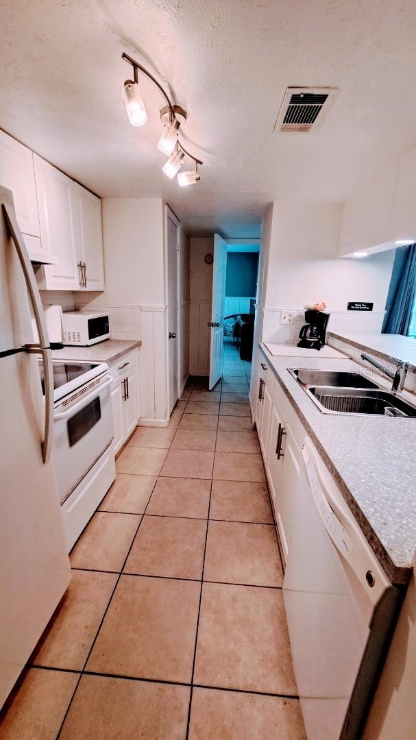 kitchen with white cabinets, white appliances, visible vents, and light countertops