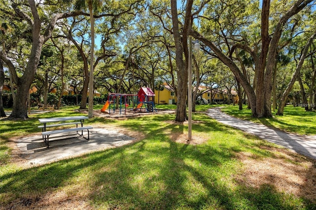 view of property's community featuring playground community and a yard