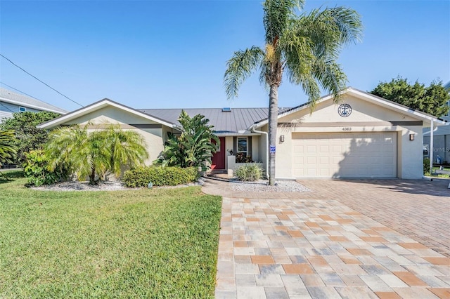 single story home with a garage, stucco siding, metal roof, decorative driveway, and a front yard