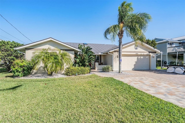 ranch-style house featuring decorative driveway, an attached garage, a front yard, and stucco siding