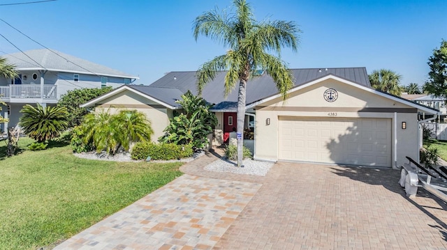 view of front of house with an attached garage, a front lawn, decorative driveway, and stucco siding