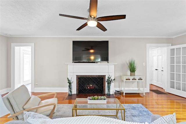 living area with crown molding, a fireplace, baseboards, and wood finished floors