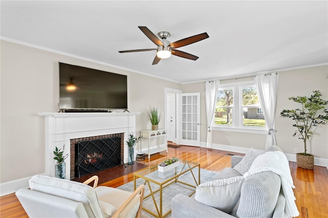 living room featuring a fireplace, baseboards, and wood finished floors