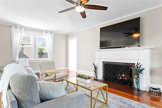 living area with ceiling fan, dark wood-style flooring, a fireplace, baseboards, and crown molding