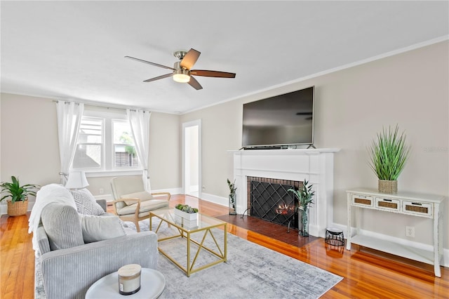 living area featuring ornamental molding, a brick fireplace, wood finished floors, and baseboards