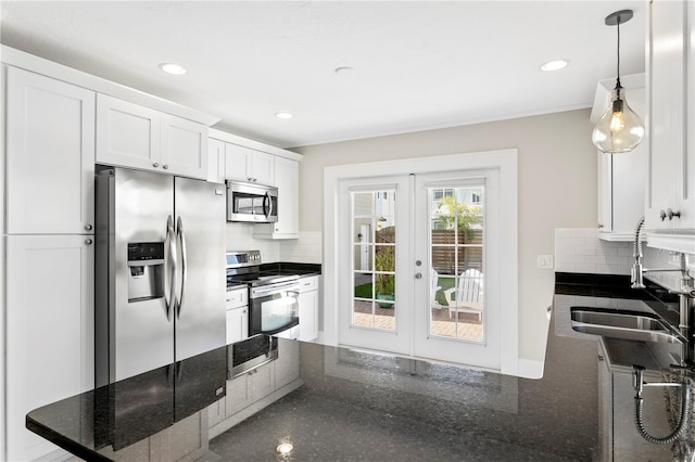 kitchen with decorative light fixtures, stainless steel appliances, decorative backsplash, white cabinetry, and a sink