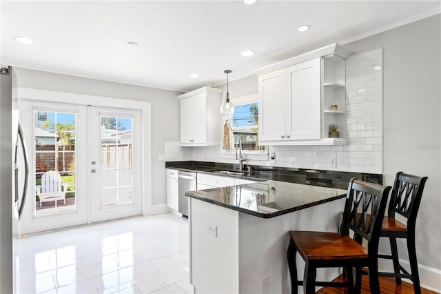 kitchen with appliances with stainless steel finishes, hanging light fixtures, a peninsula, white cabinetry, and open shelves