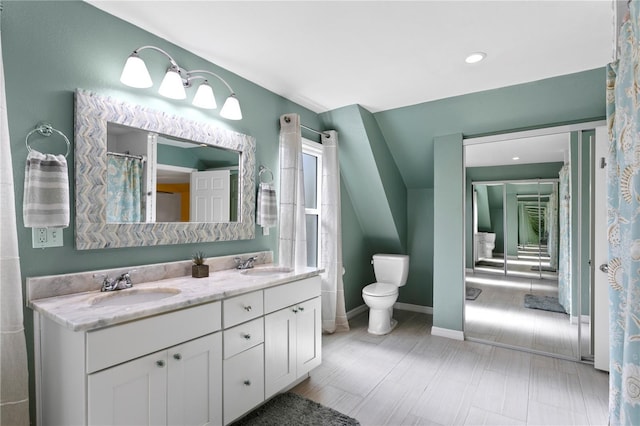 bathroom with double vanity, baseboards, toilet, and a sink