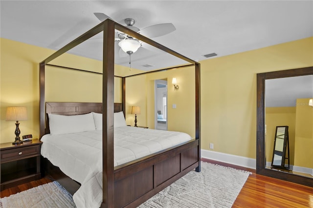 bedroom with visible vents, ceiling fan, baseboards, and wood finished floors