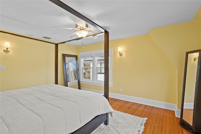 bedroom featuring a ceiling fan, baseboards, visible vents, and wood finished floors