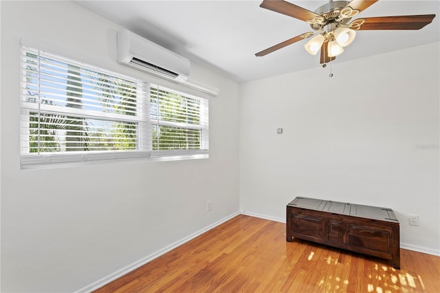 empty room featuring light wood finished floors, baseboards, a ceiling fan, and a wall mounted air conditioner