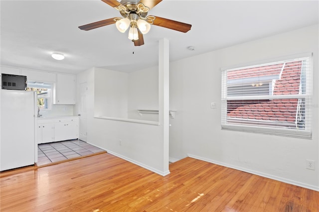 unfurnished room with light wood finished floors, baseboards, and a ceiling fan