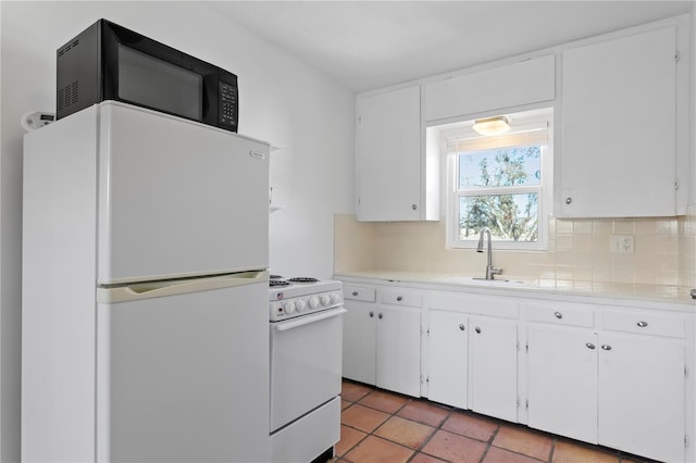 kitchen featuring white appliances, tasteful backsplash, white cabinets, light countertops, and a sink