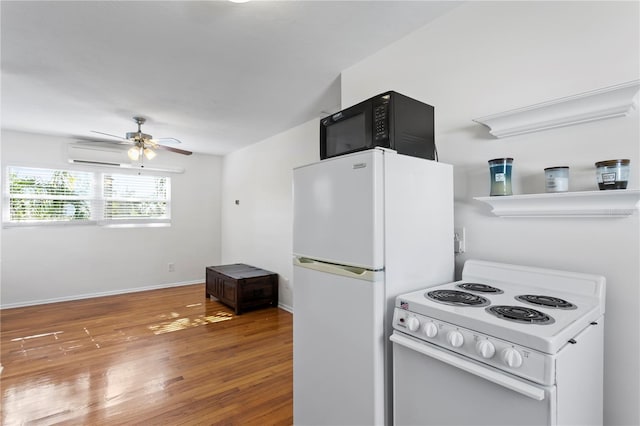 kitchen featuring a wall mounted AC, a ceiling fan, wood finished floors, white appliances, and baseboards