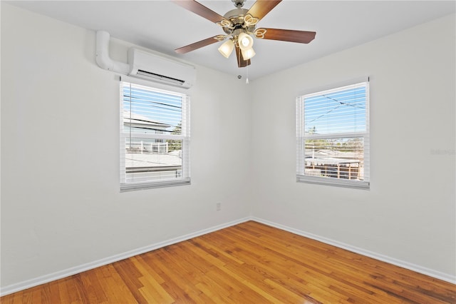 empty room featuring baseboards, wood finished floors, a wealth of natural light, and a wall mounted AC