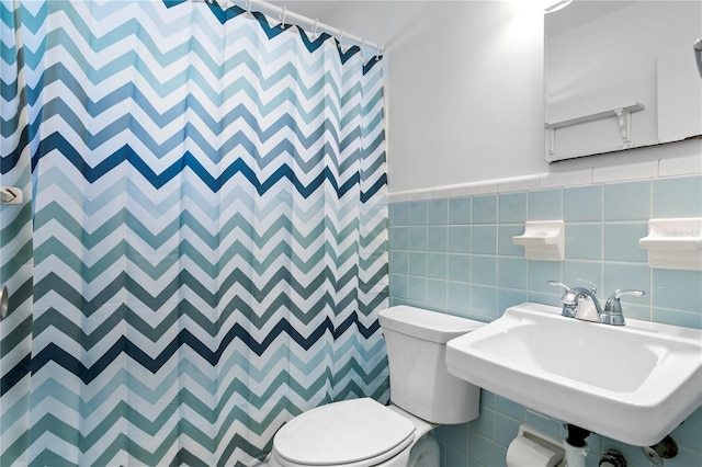 bathroom with tile walls, a sink, toilet, and a shower with curtain