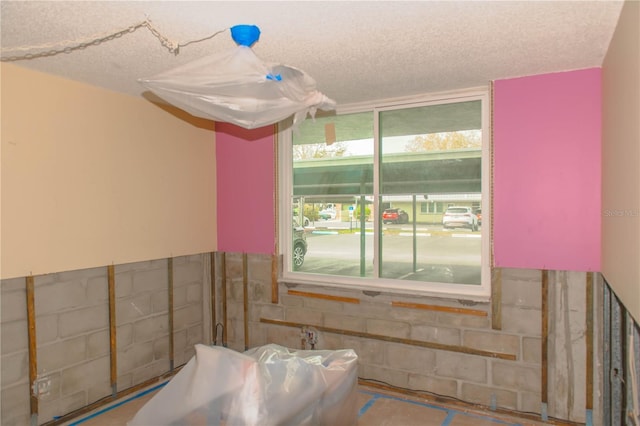 bathroom featuring a textured ceiling and concrete block wall