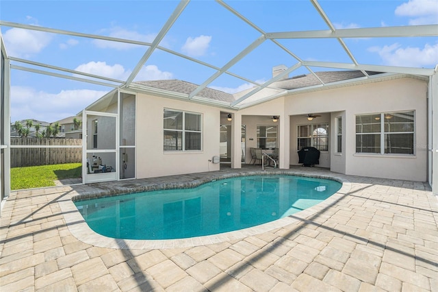 view of pool with a fenced in pool, glass enclosure, and a ceiling fan