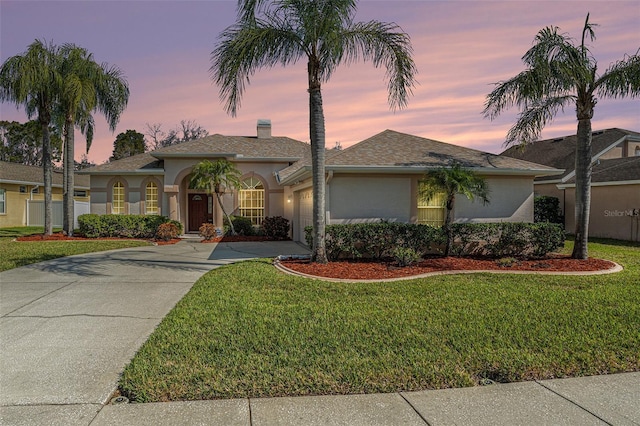 ranch-style home featuring a garage, concrete driveway, a front lawn, and stucco siding