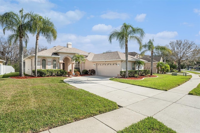 mediterranean / spanish-style house with a front yard, concrete driveway, an attached garage, and stucco siding