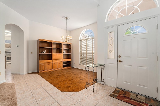 entrance foyer with light tile patterned floors, arched walkways, and a chandelier