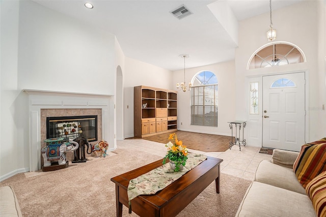 living area with visible vents, an inviting chandelier, light carpet, a tile fireplace, and baseboards