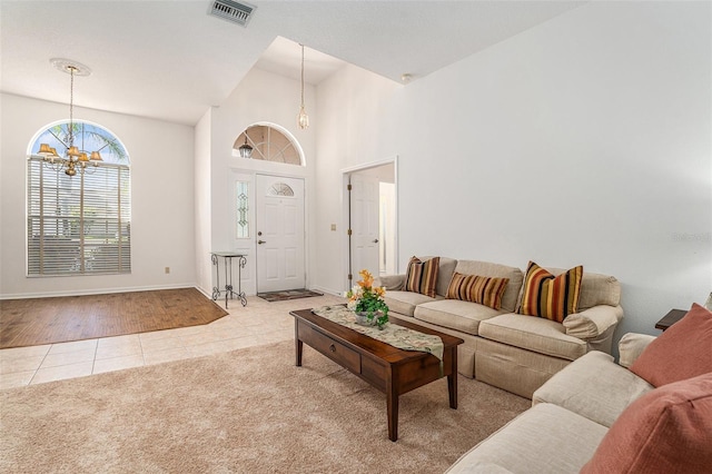 living area featuring light tile patterned floors, visible vents, a high ceiling, an inviting chandelier, and light carpet