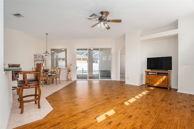 living room with arched walkways, wood finished floors, visible vents, and a ceiling fan