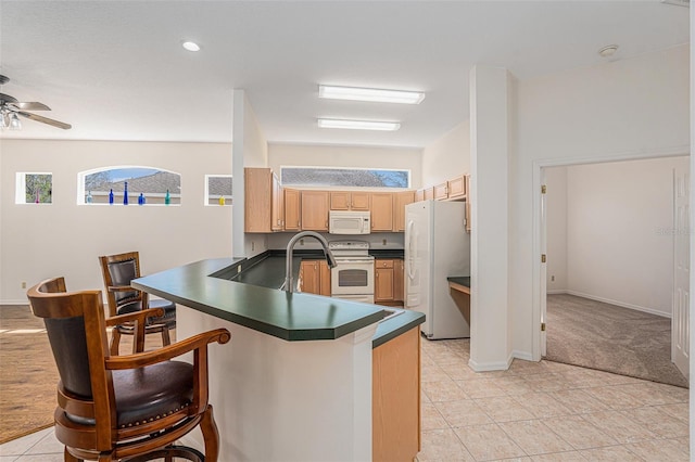 kitchen with a peninsula, white appliances, a breakfast bar area, and dark countertops