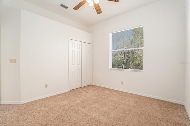 unfurnished bedroom featuring baseboards, a closet, visible vents, and light colored carpet