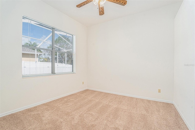 carpeted spare room featuring a ceiling fan and baseboards