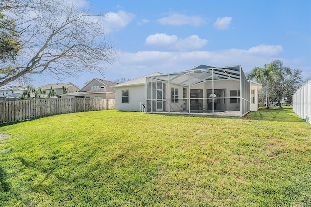 rear view of property with a patio area, a lanai, a fenced backyard, and a lawn