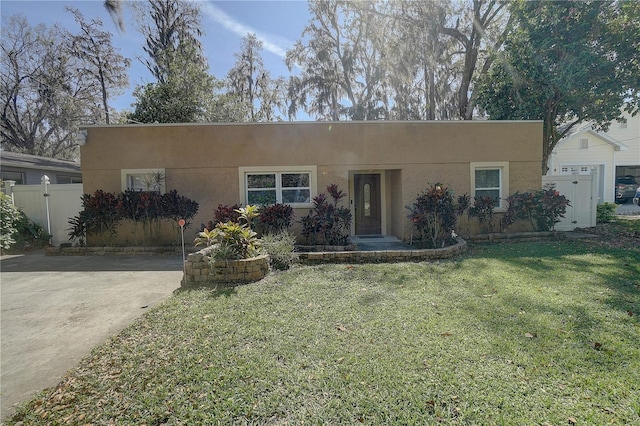 view of front of property with a front yard, fence, and stucco siding