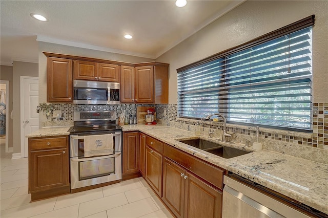 kitchen with stainless steel appliances, a sink, backsplash, light stone countertops, and crown molding