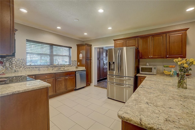 kitchen featuring light stone counters, a toaster, stainless steel appliances, tasteful backsplash, and a sink