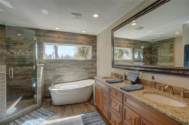 bathroom featuring a soaking tub, a shower stall, a sink, and wood finished floors